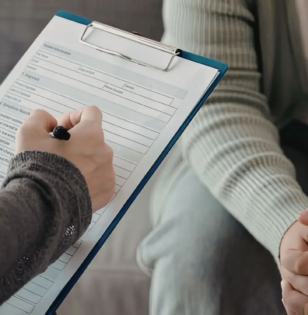 Doctor points to document on clipboard for a patient, likely discussing medical information.