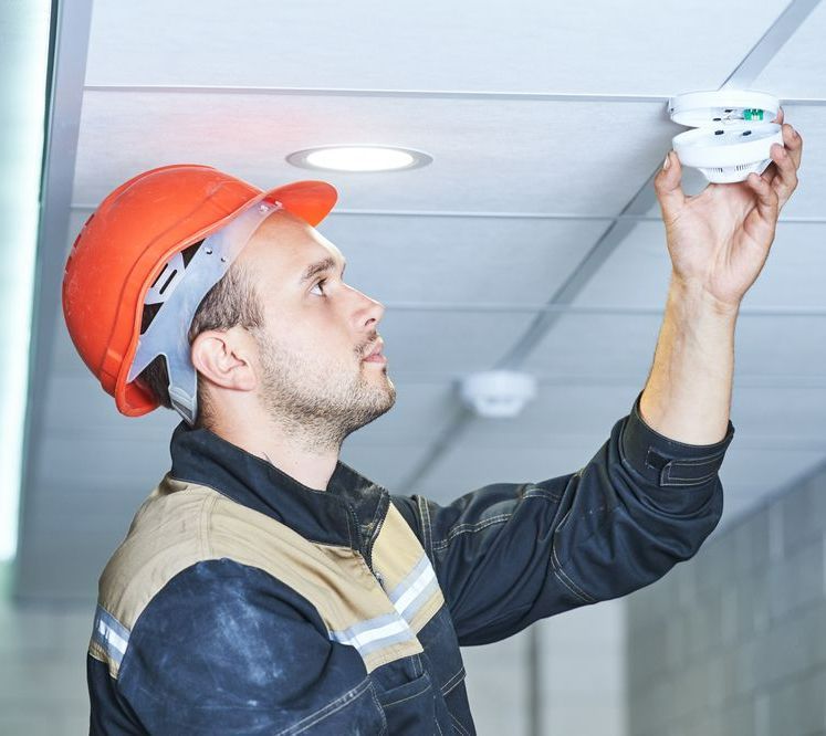 A Man Wearing A Hard Hat Is Installing — Chris North Electrical In Jones Hill, QLD