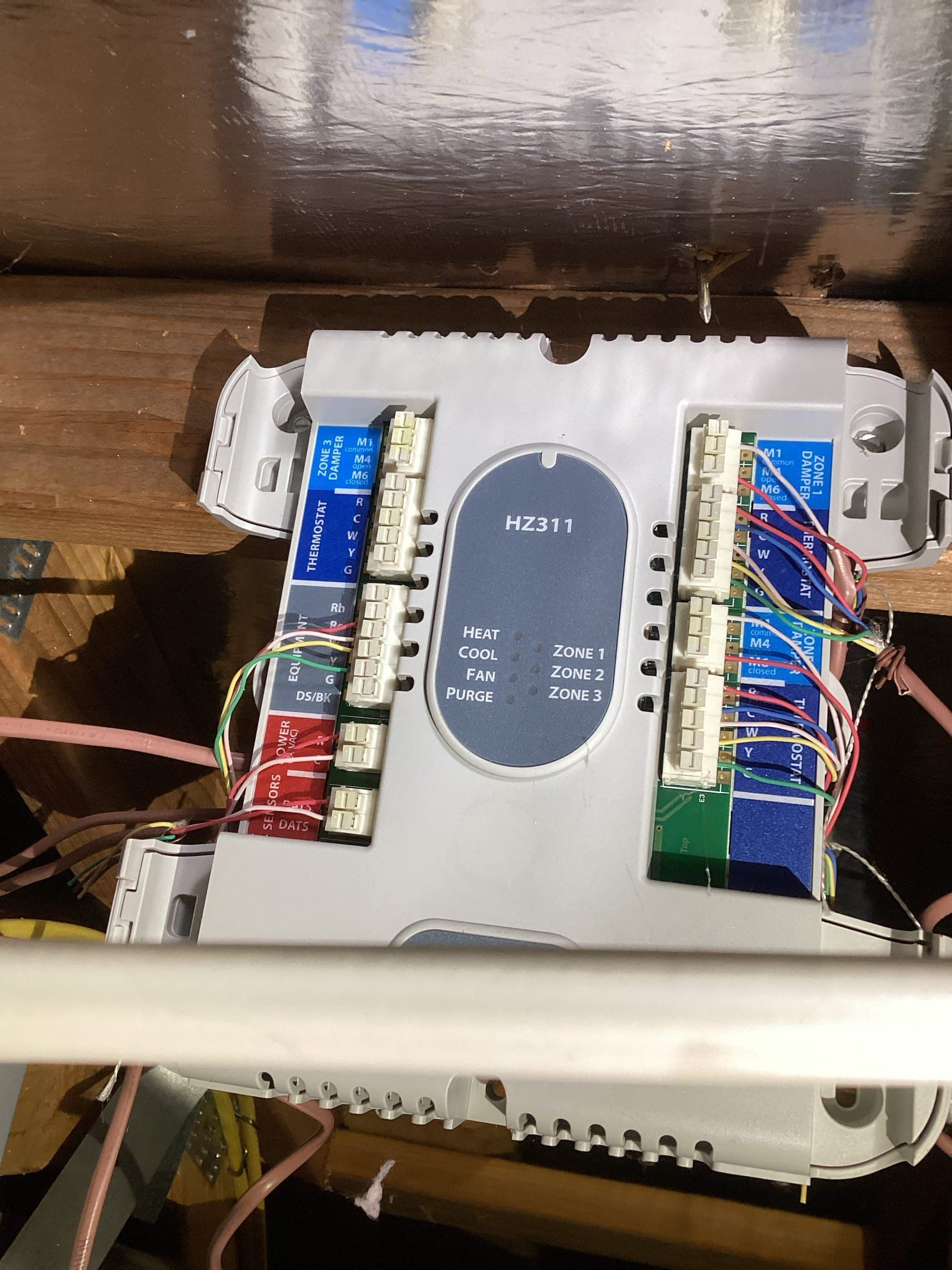 Telephone wiring box with multiple colored wires and ports, mounted on wood.