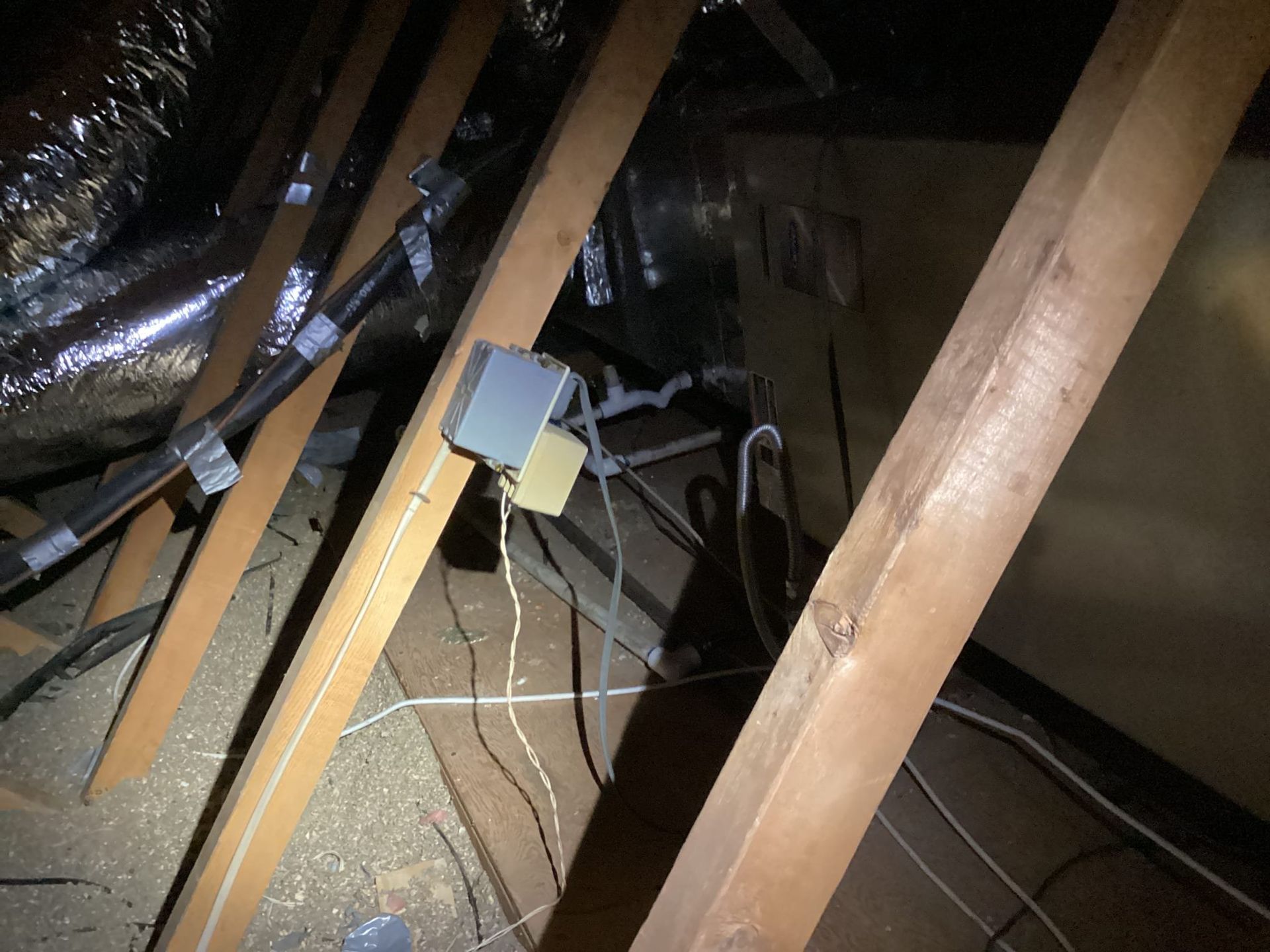 Attic interior view with wooden beams, electrical box, and ductwork.