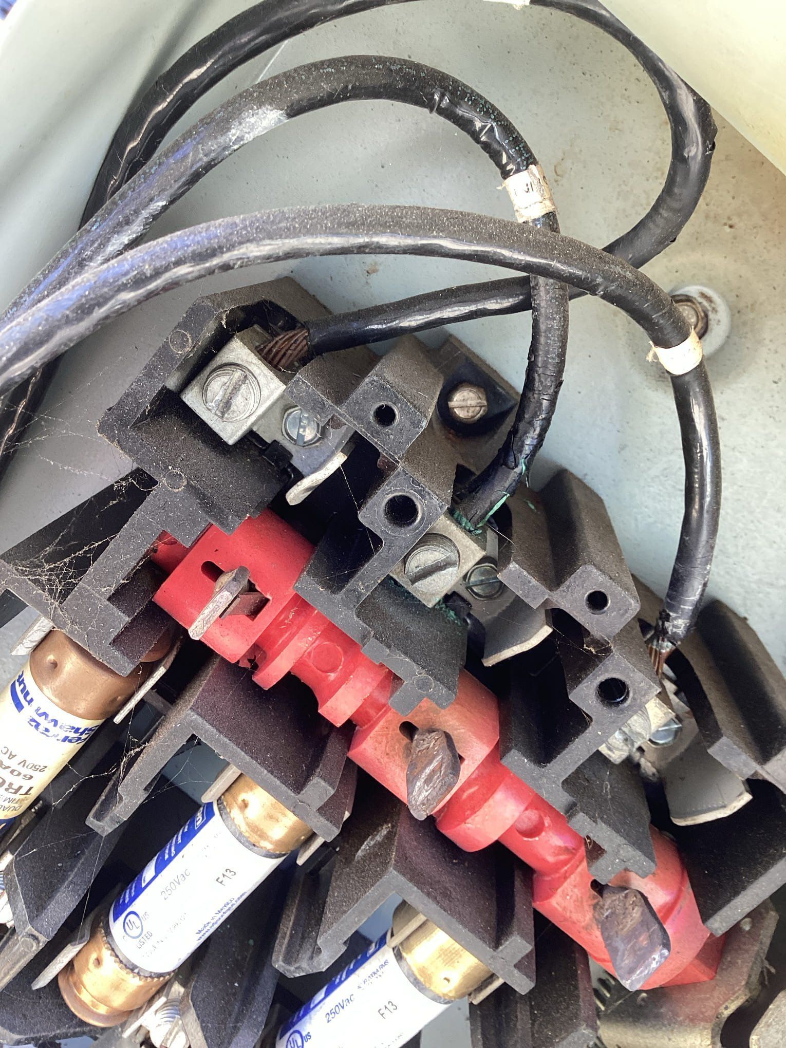 Close-up of electrical fuses with red and black wiring in a metal enclosure.