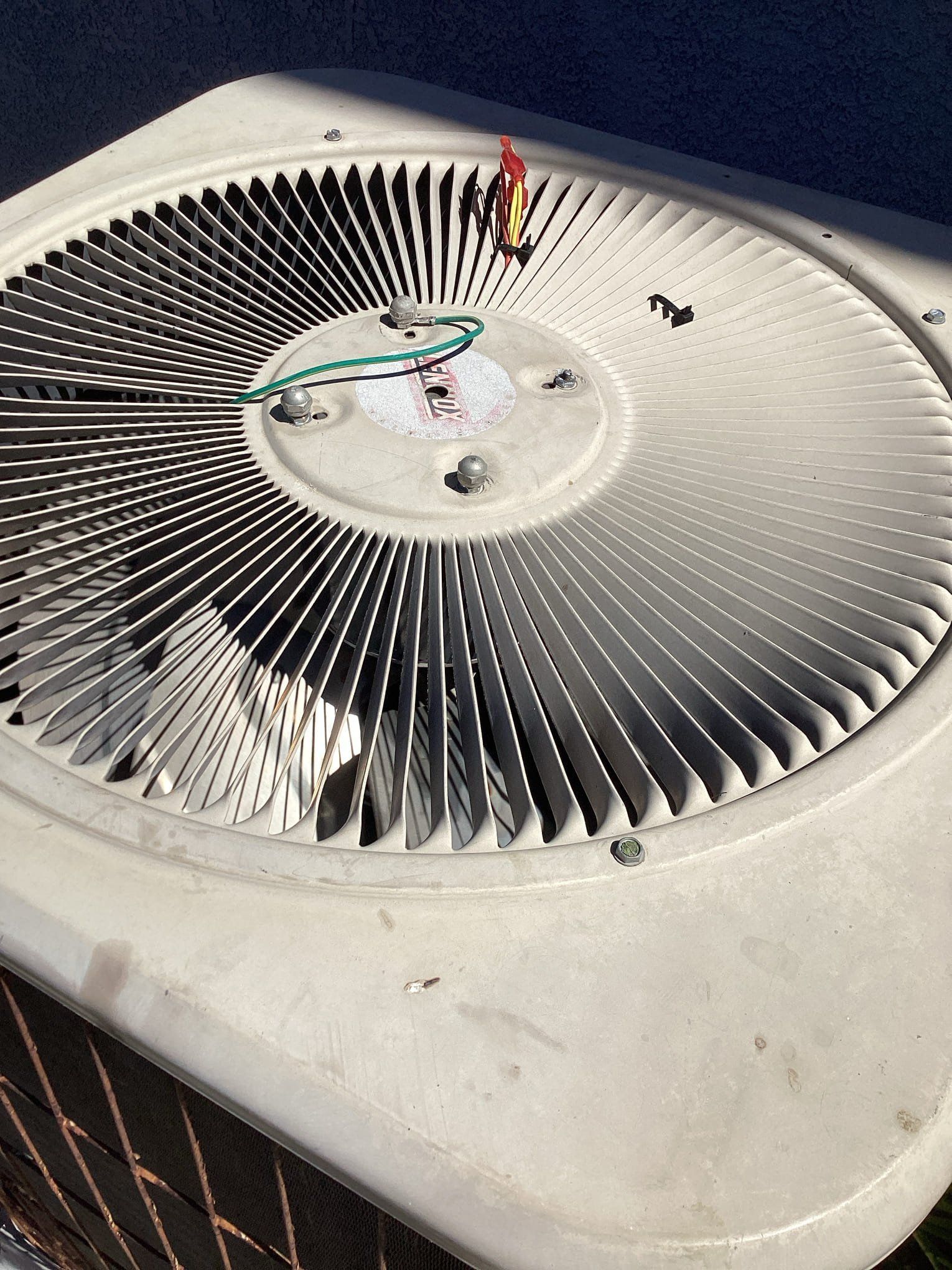An air conditioning unit with a fan and wiring visible. White plastic casing with metal fins.