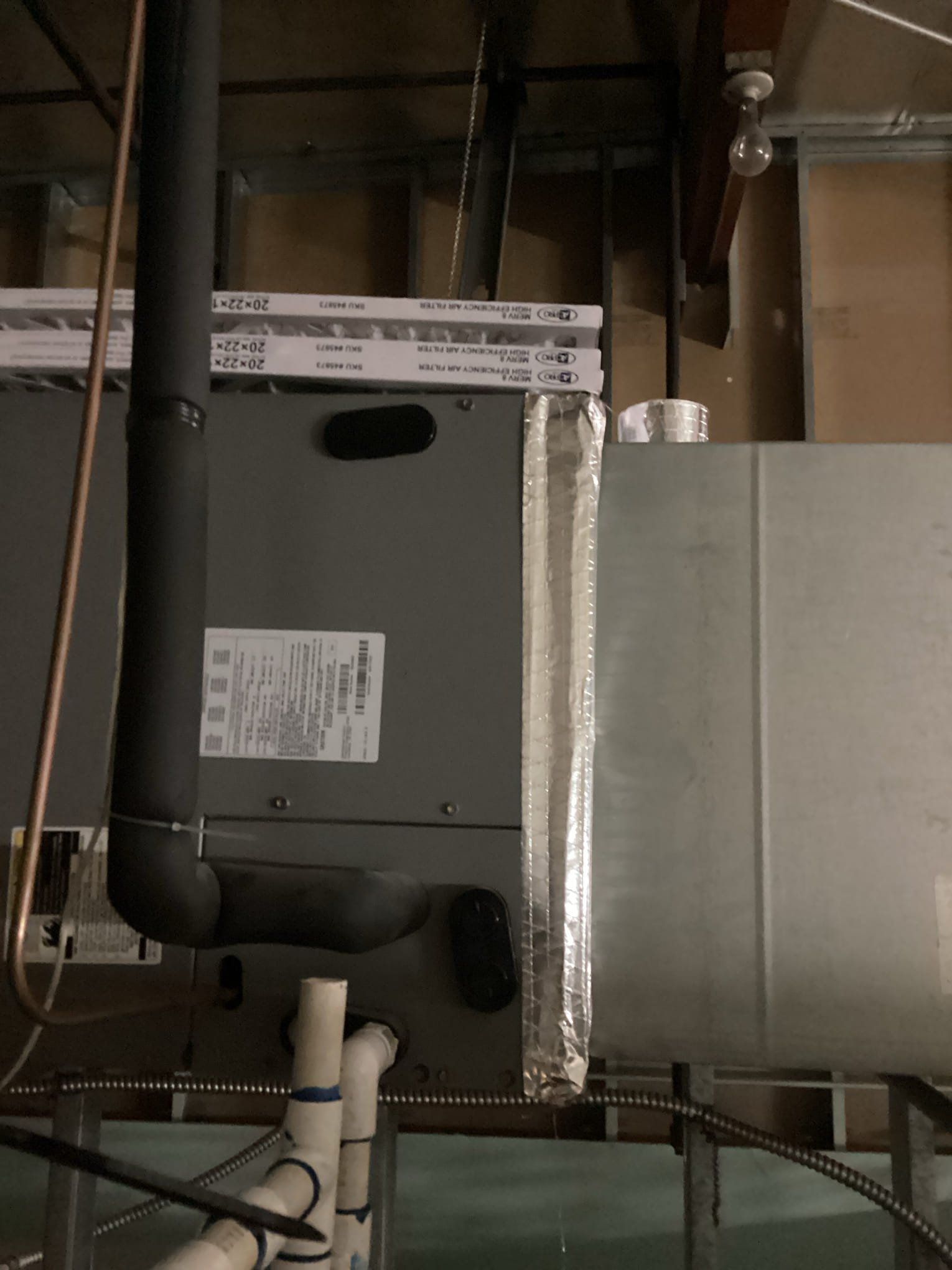HVAC unit with insulated ductwork and piping in an unfinished space.