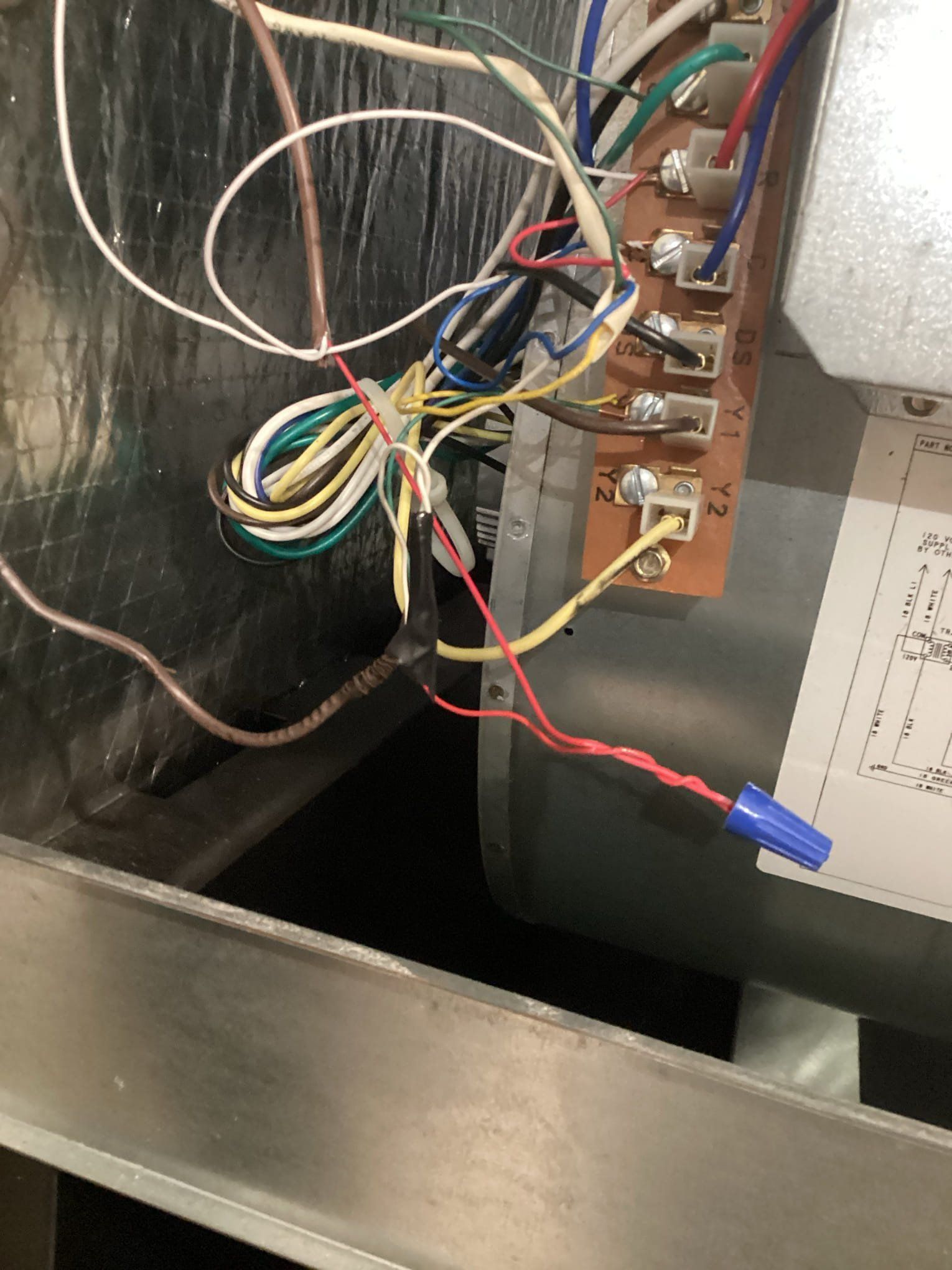 Wiring connections inside an HVAC unit, featuring wires of various colors and a wire connector.