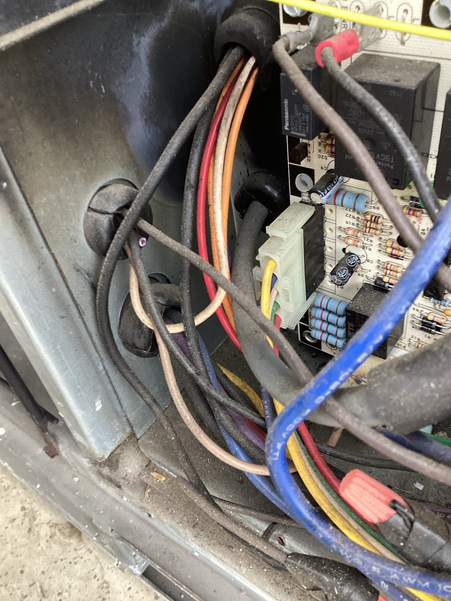 Electrical wires inside an air conditioning unit; multiple colored wires connected to a circuit board.