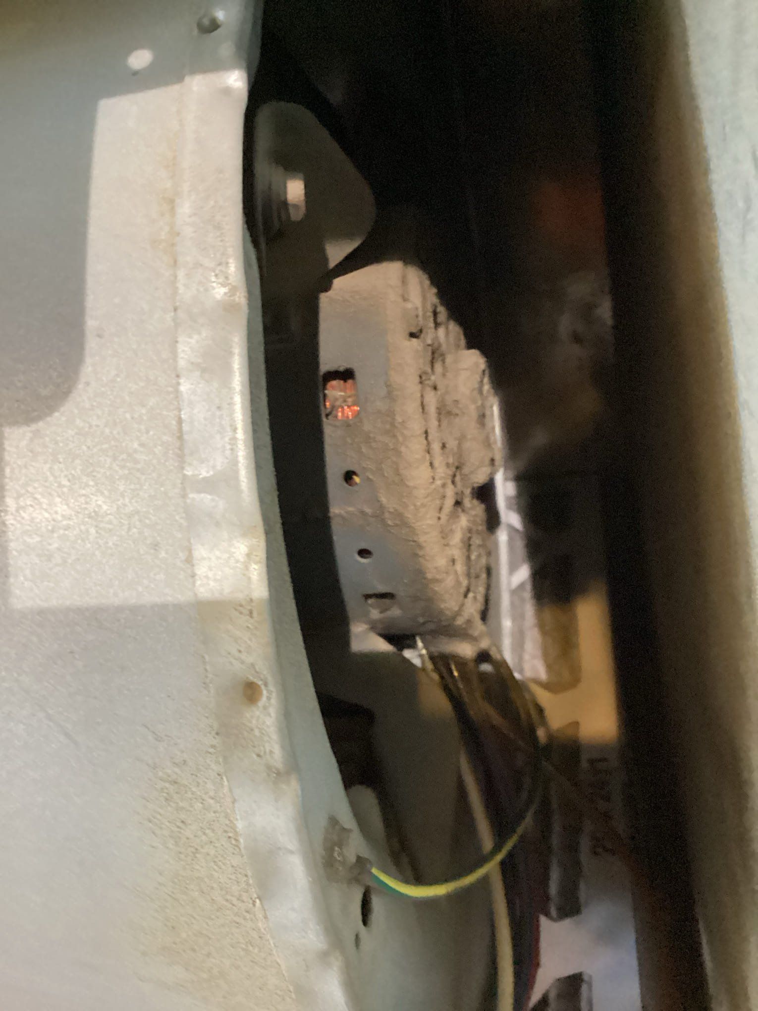 Dusty rectangular object attached to metal frame, wires visible, viewed from inside.