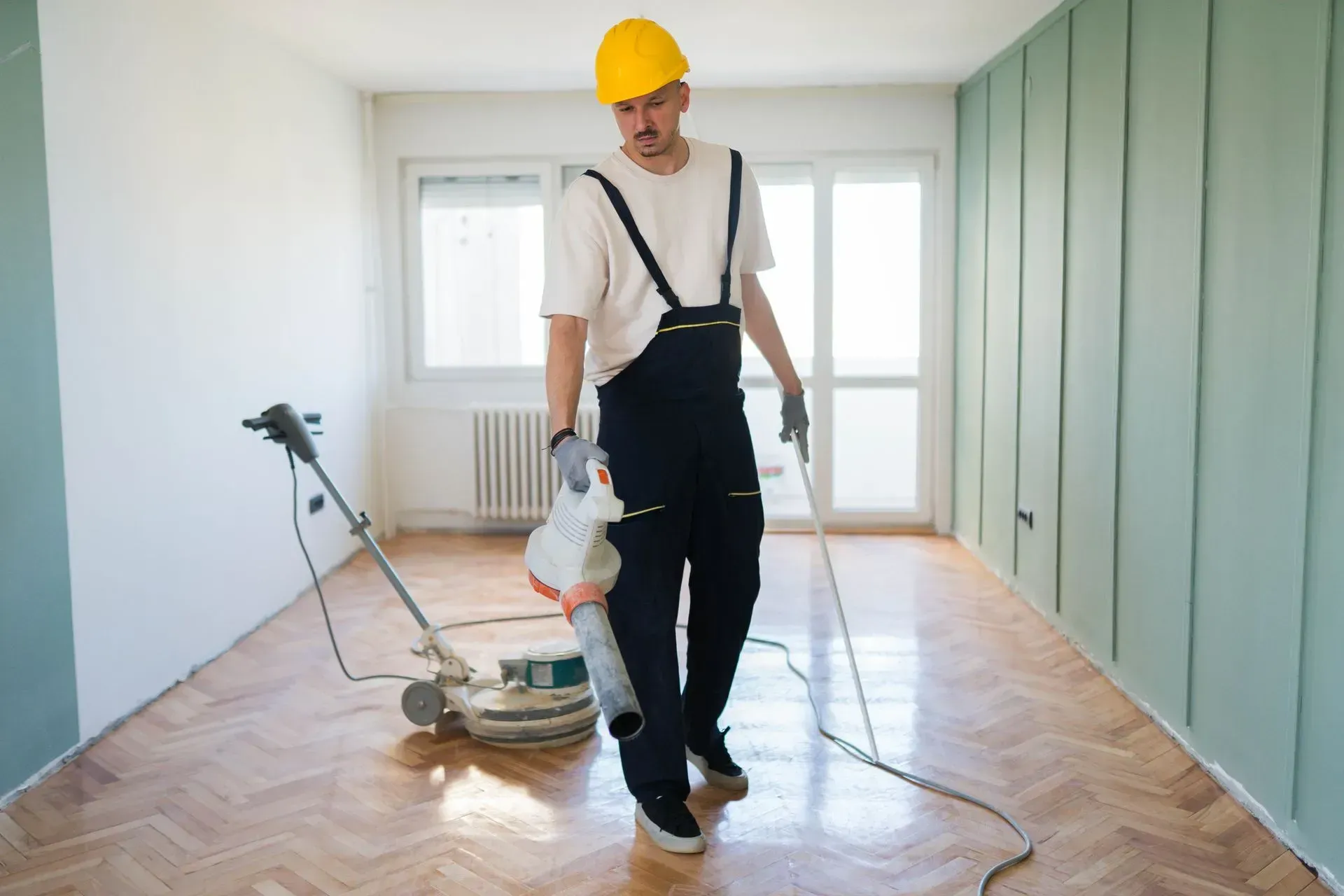 Technician polishing parquet flooring during expert tile floor cleaning services in a living room.