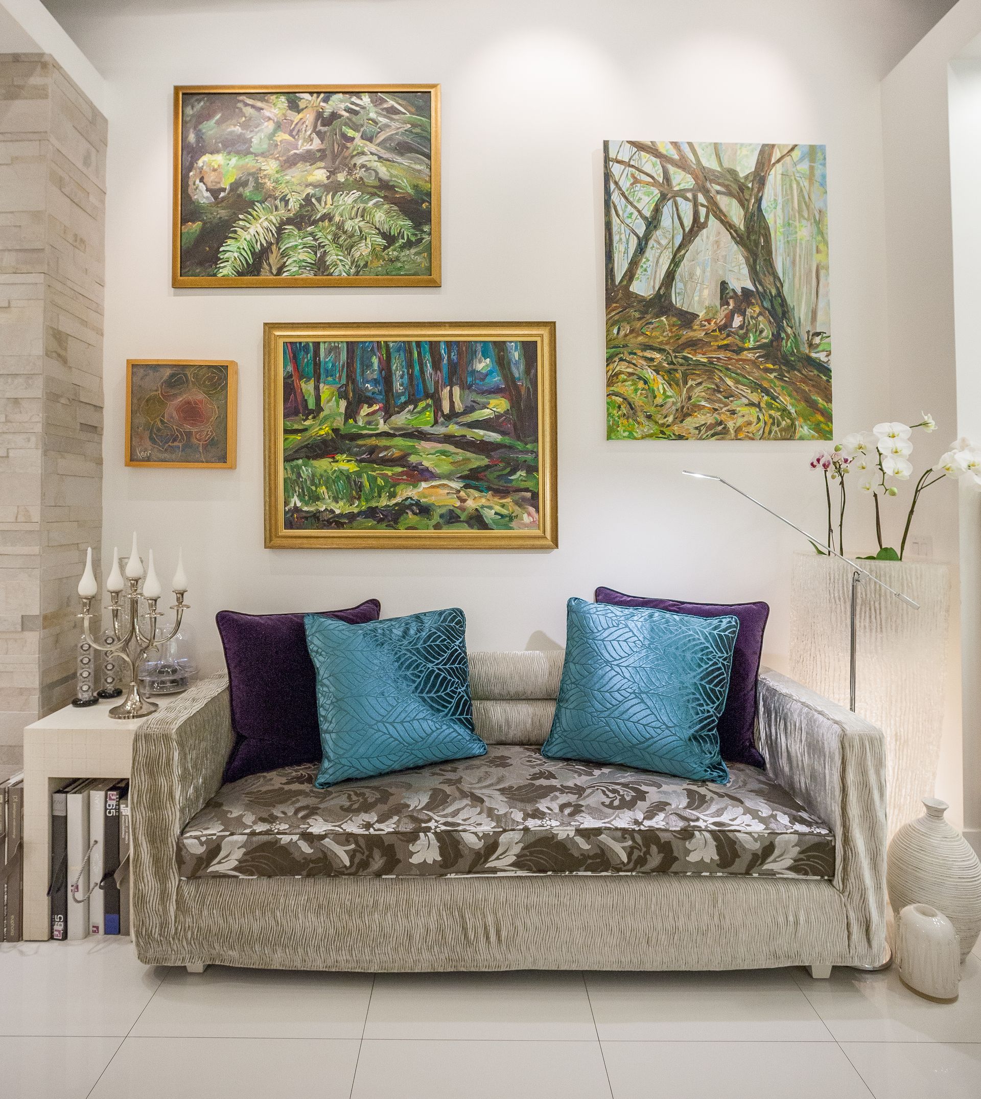 Sofa in a showroom with three pieces of Hilary Kerr art hung on the walls. 