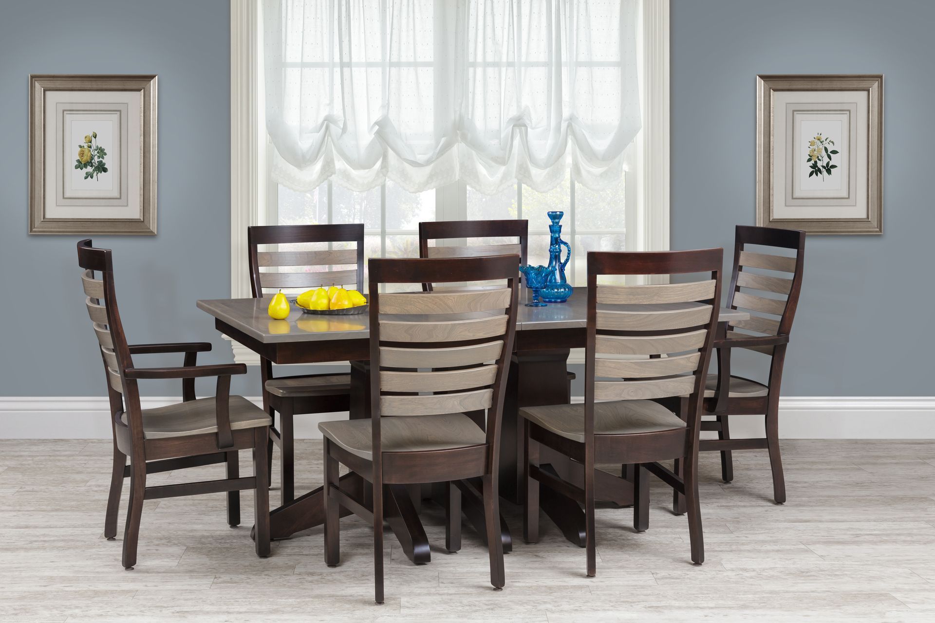 A dining room with a table and chairs in front of a window.