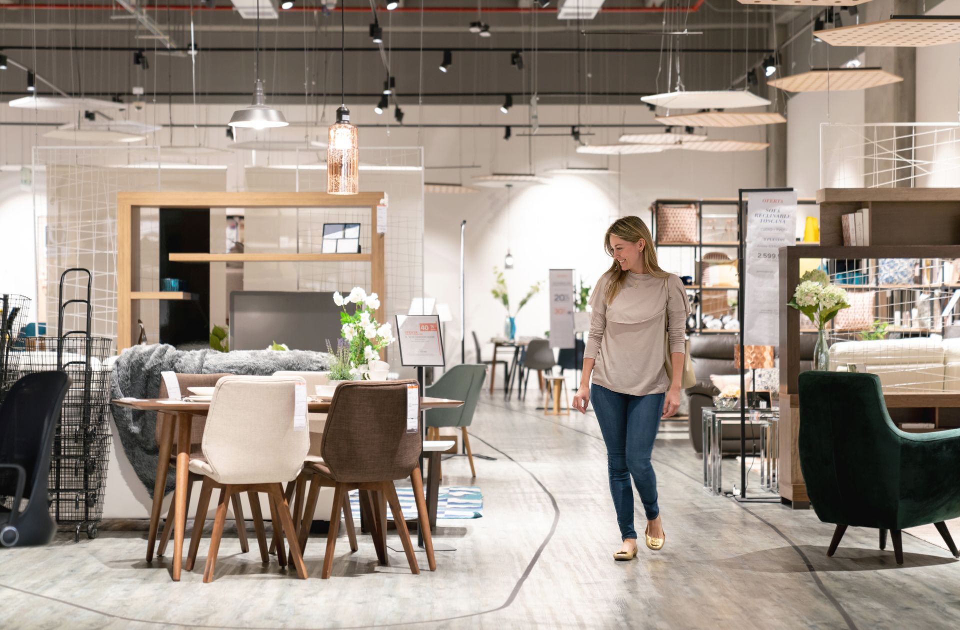Happy woman shopping at a furniture store and looking at a dining room while smiling.