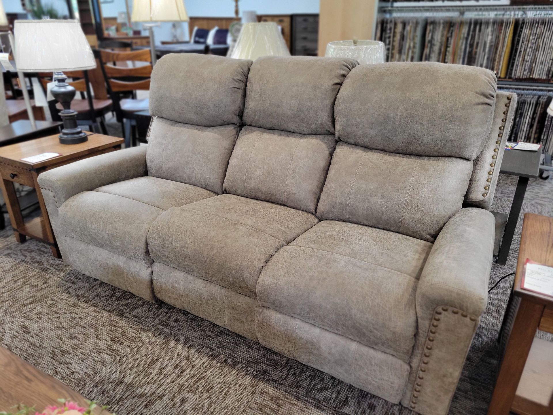 A beige recliner couch is sitting on a rug in a living room.