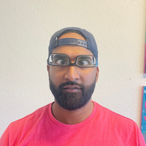 A man with a beard wearing glasses and a baseball cap