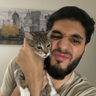 A man with a beard is holding a cat in his arms