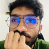 A man wearing glasses has his hand on his chin