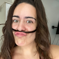 A woman is making a funny face with a fake mustache.