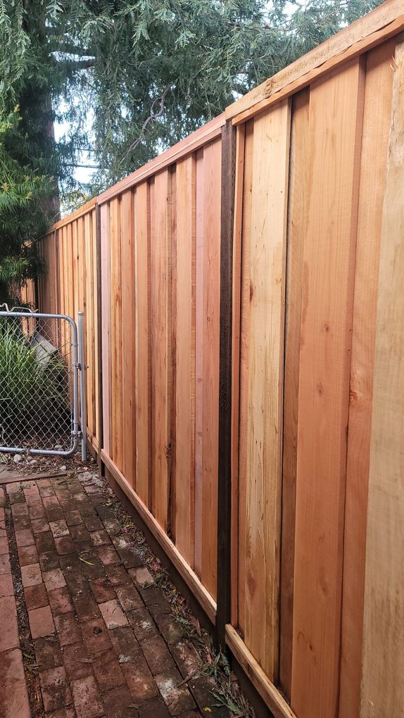 Wooden fence with a gate, next to a brick pathway.