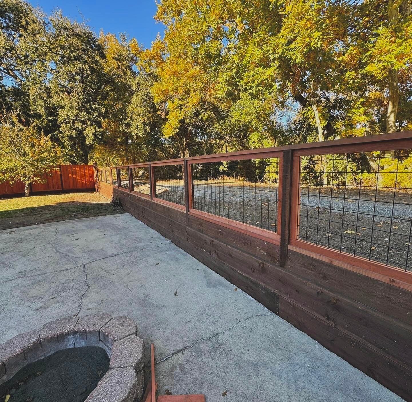 A wooden fence with metal mesh panels.