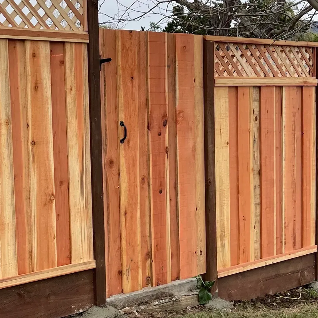 Wooden fence with gate, light brown color. Lattice top and dark brown base.