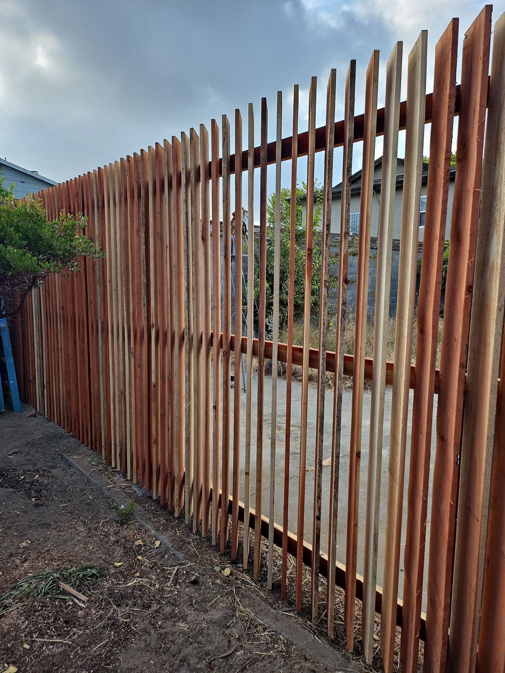 Wooden fence made of vertical, uneven logs. Brown and tan colors.