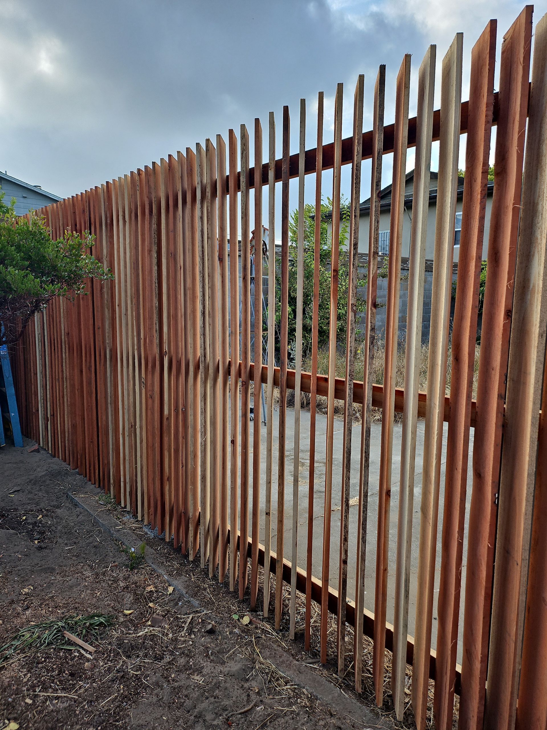 Wooden fence made of vertical, uneven logs. Brown and tan colors.