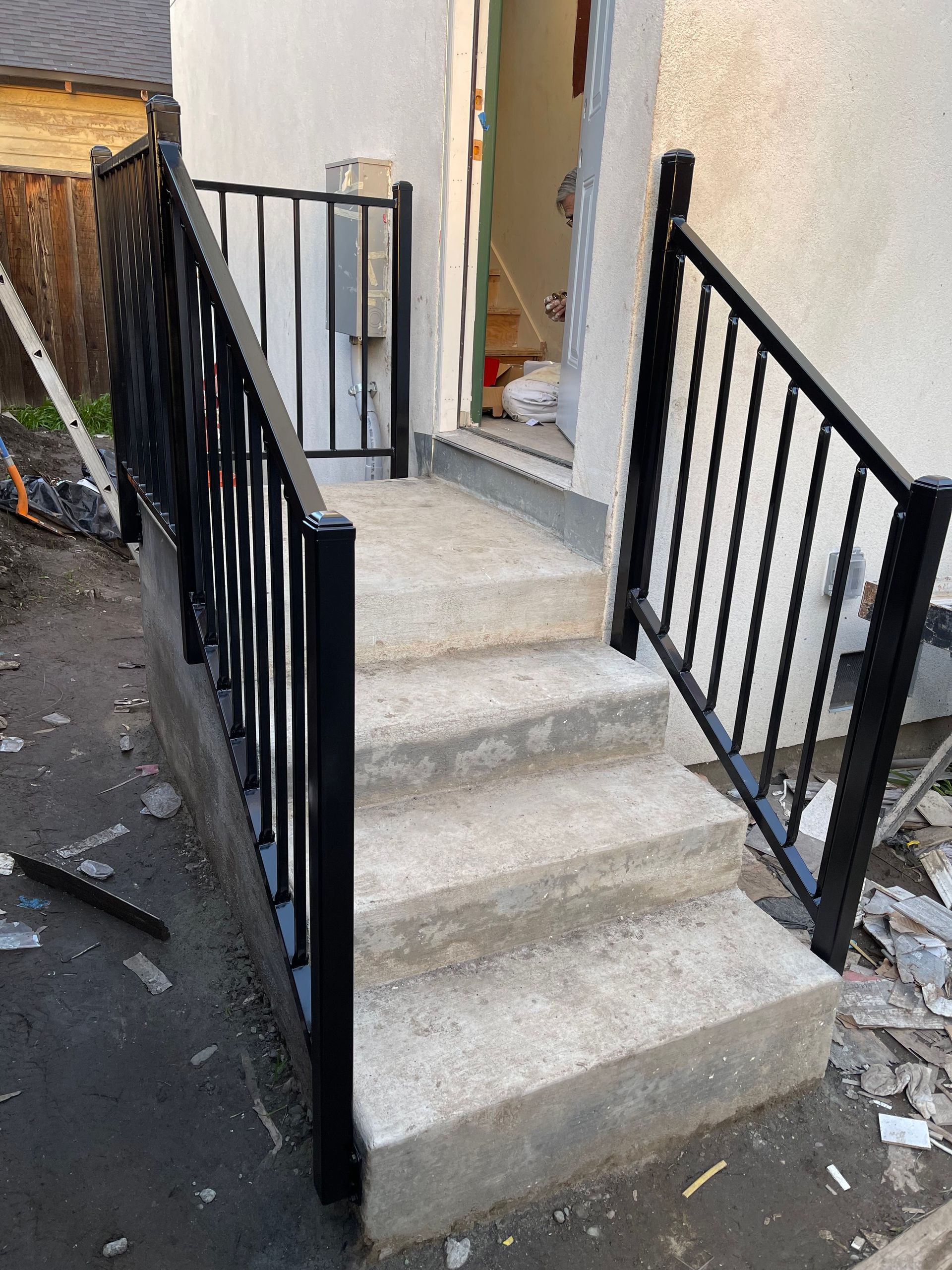 Concrete steps with black metal railings lead to a doorway.