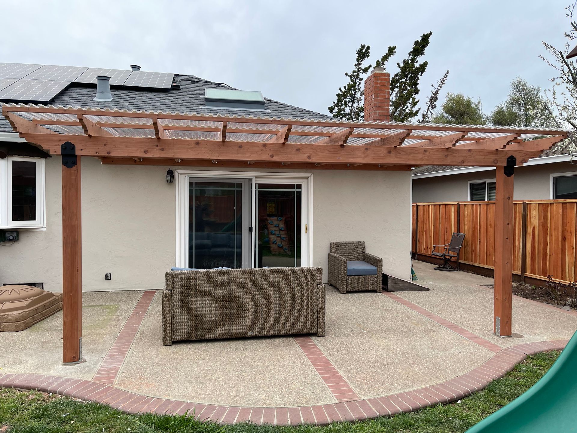 Patio with a wooden pergola, outdoor furniture, and a sliding glass door.