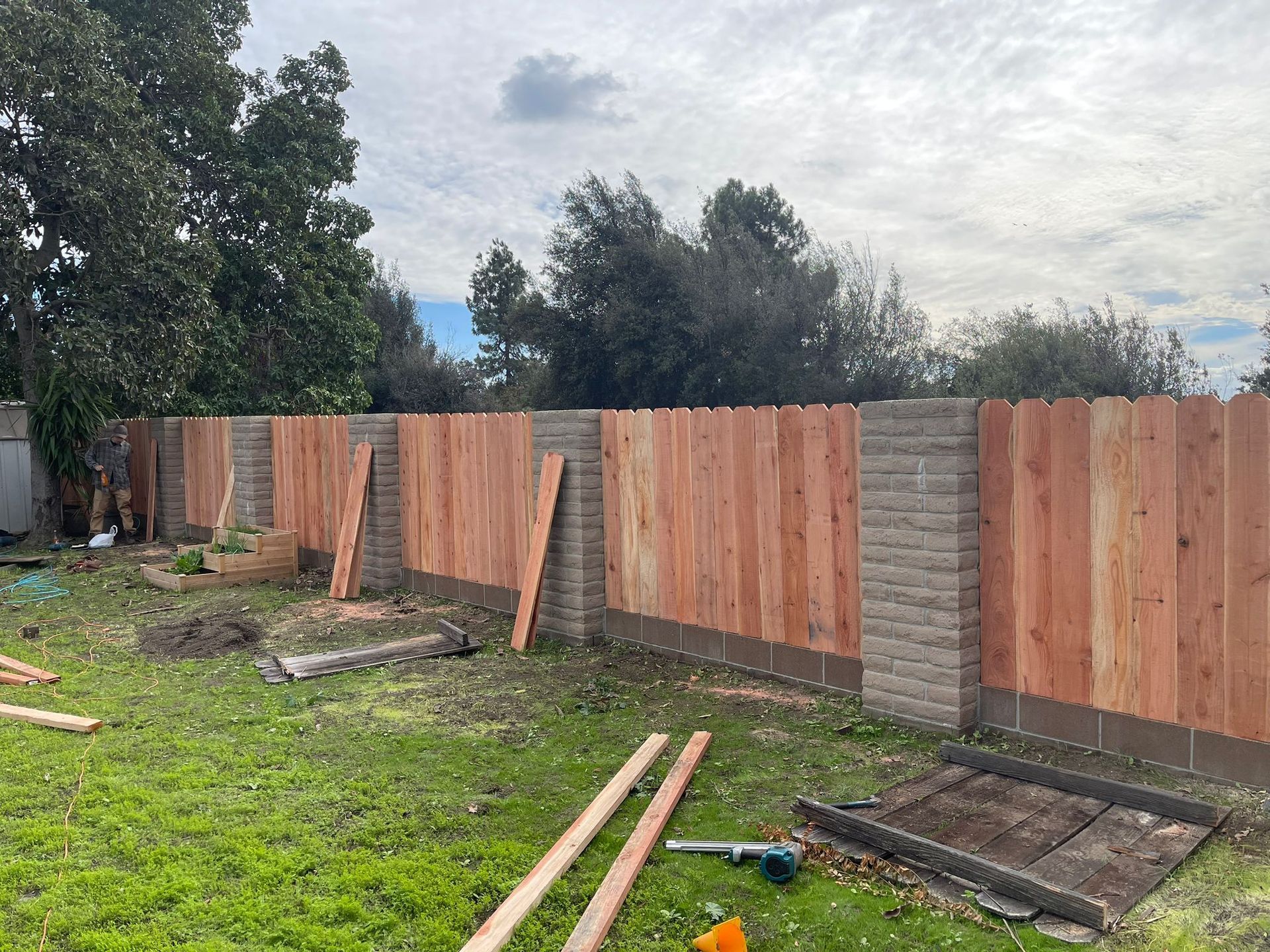 Wooden fence panels attached to concrete block posts, in a grassy yard.