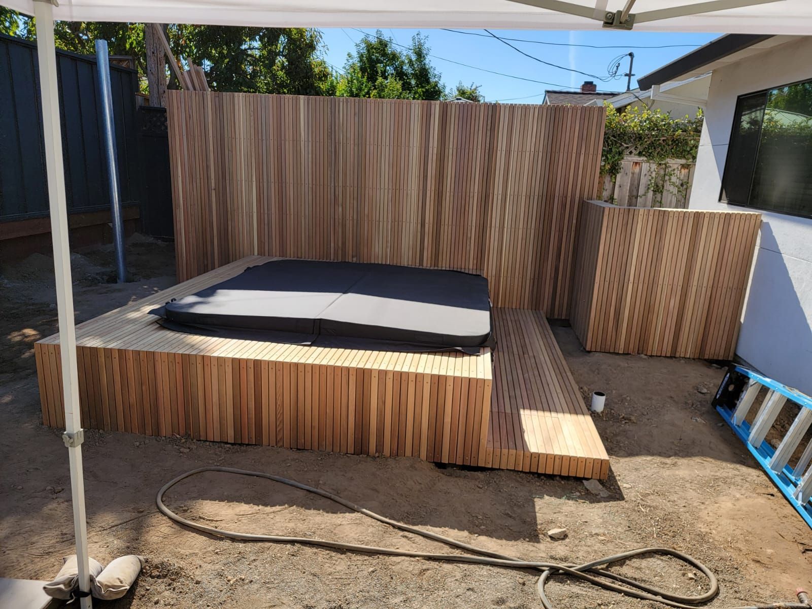 Wooden hot tub deck with privacy fence in backyard.