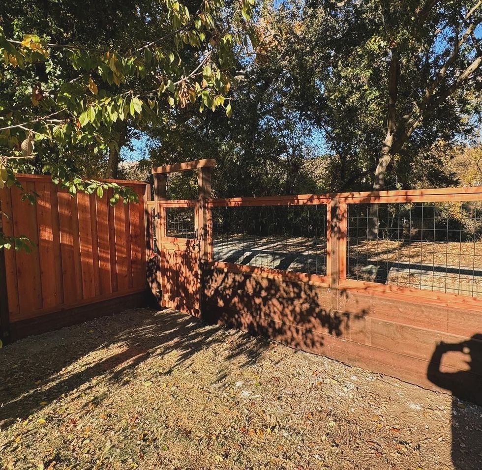 Wooden fence and gate with trees and shadows.
