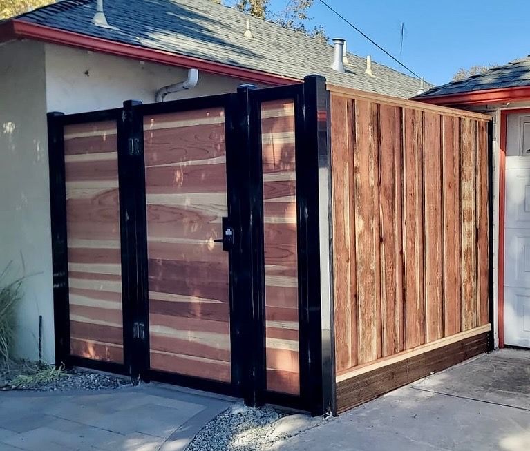 Wooden fence and gate with black metal frame outside a building.