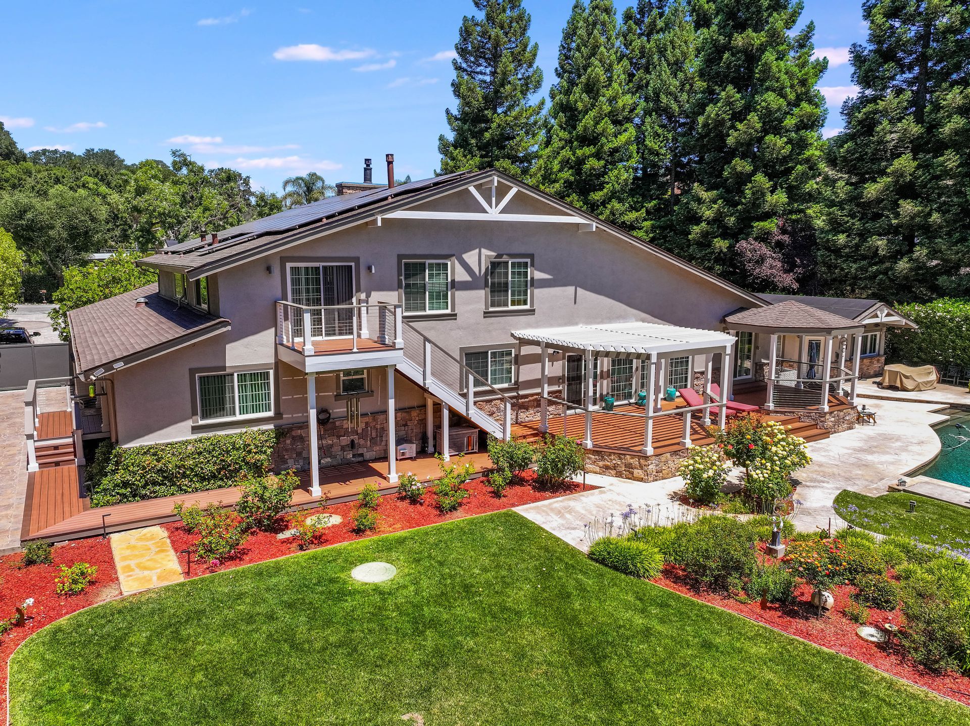 Large gray house with white trim, front porch, and landscaped yard under a blue sky