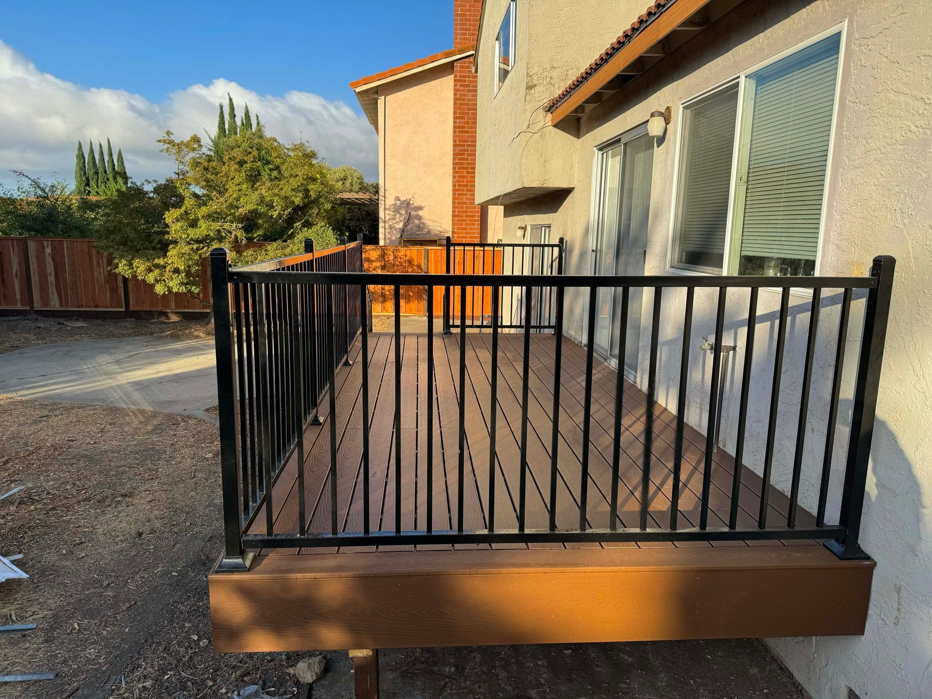 Patio with pergola, furniture, and sliding glass door. Brown wood, tan stucco, and brick trim.