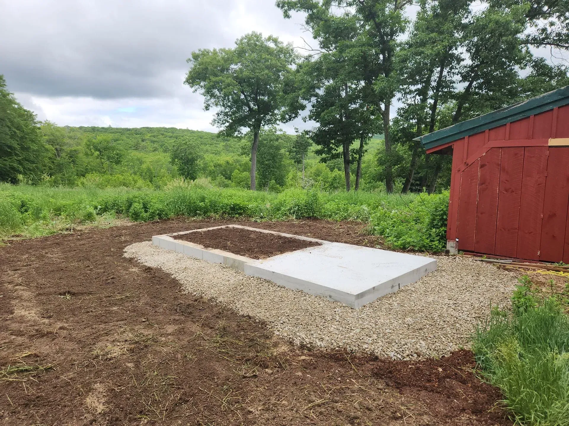 A red barn is sitting in the middle of a dirt field.
