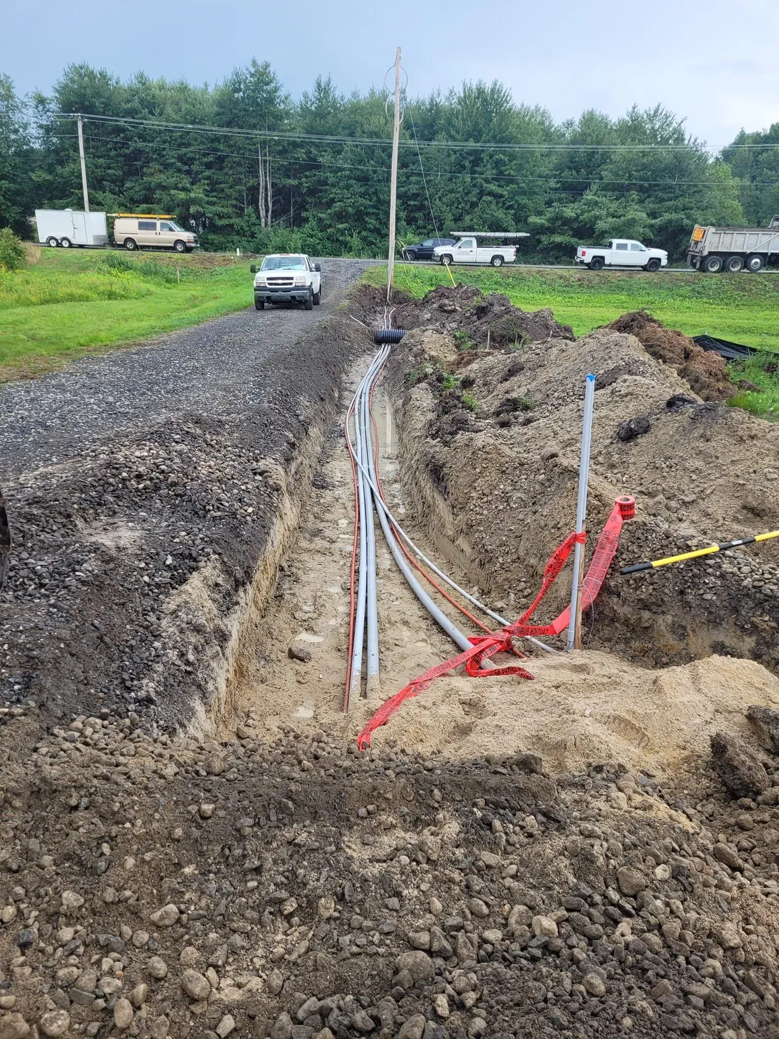 A car is driving down a dirt road next to a field.