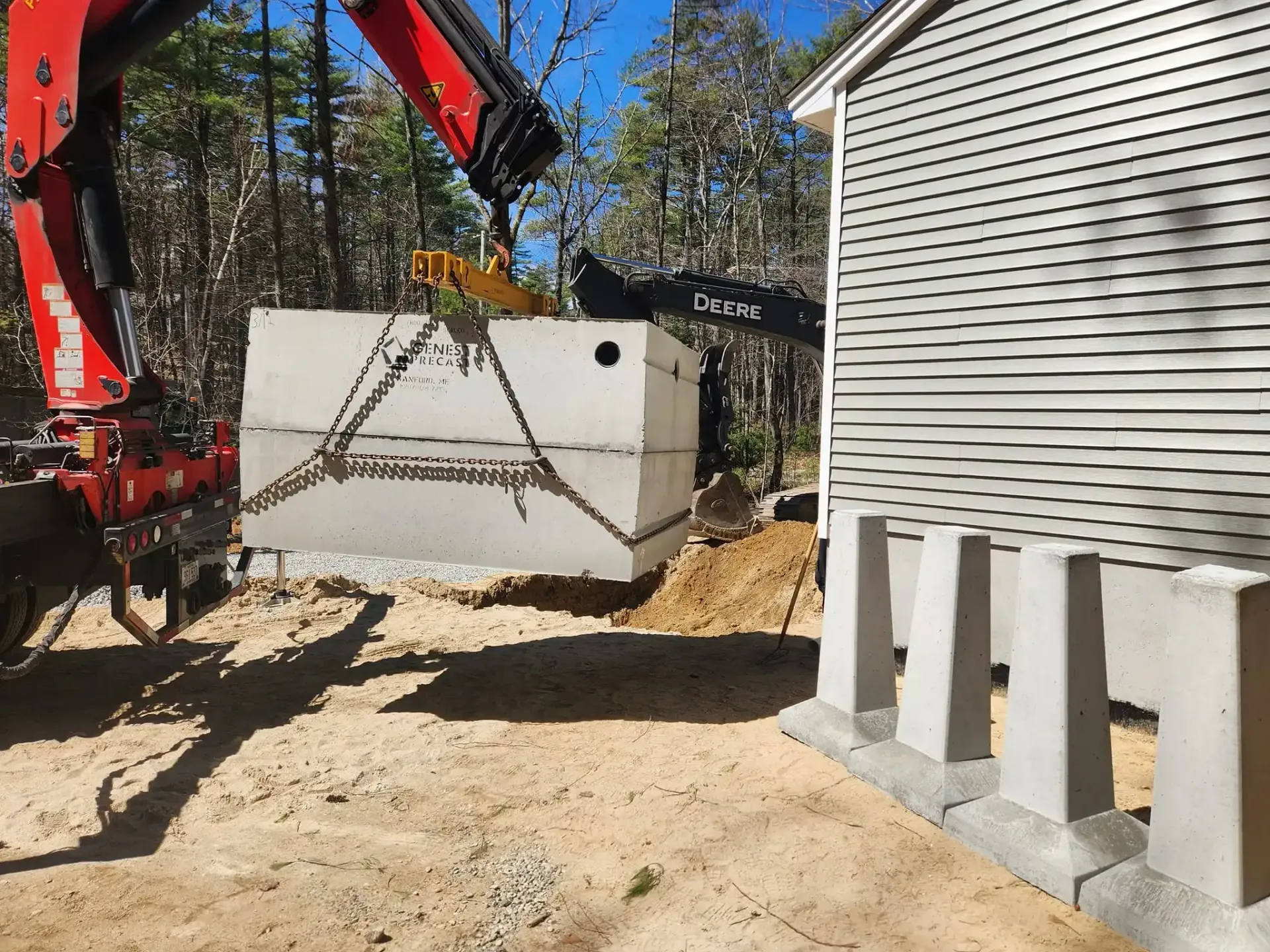 A crane is lifting a large concrete block in front of a house.
