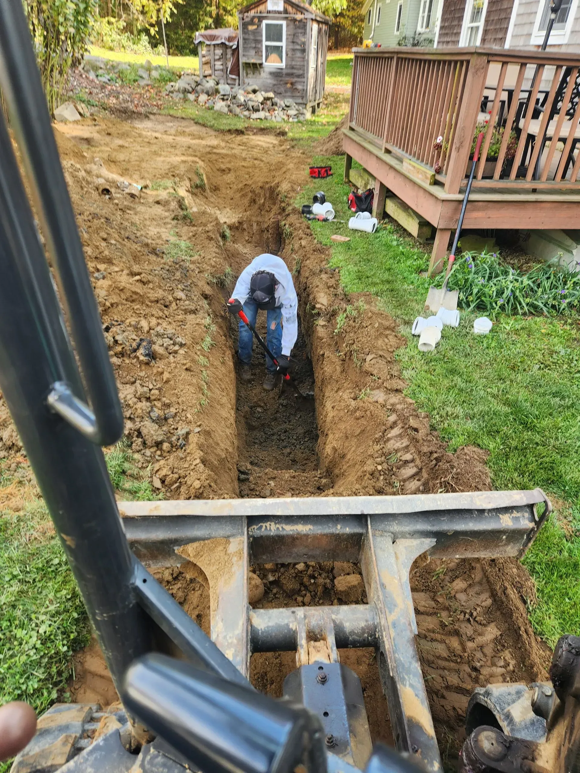 A man is digging a hole in the ground in front of a house.