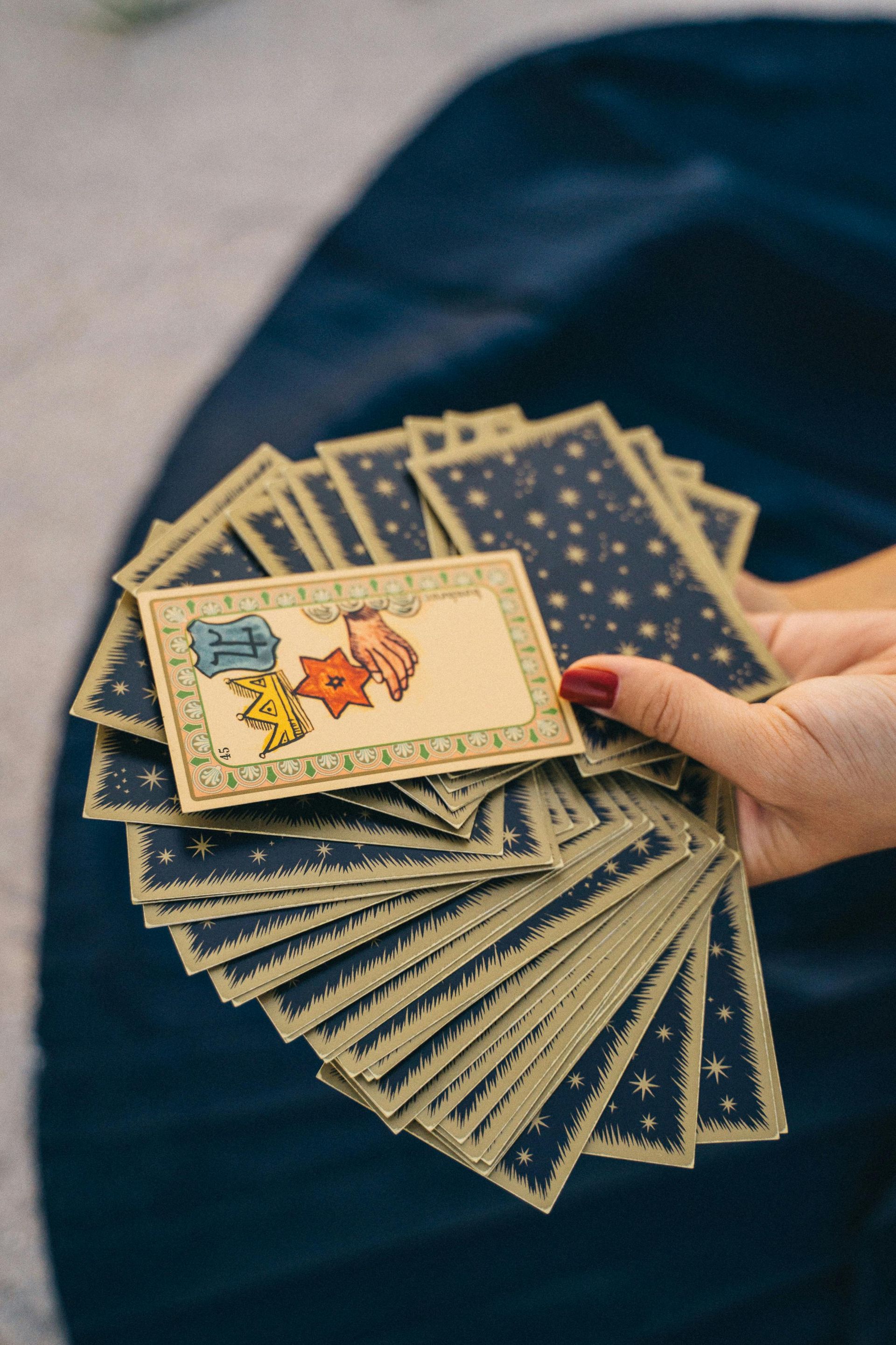 A person is holding a stack of tarot cards in their hand.