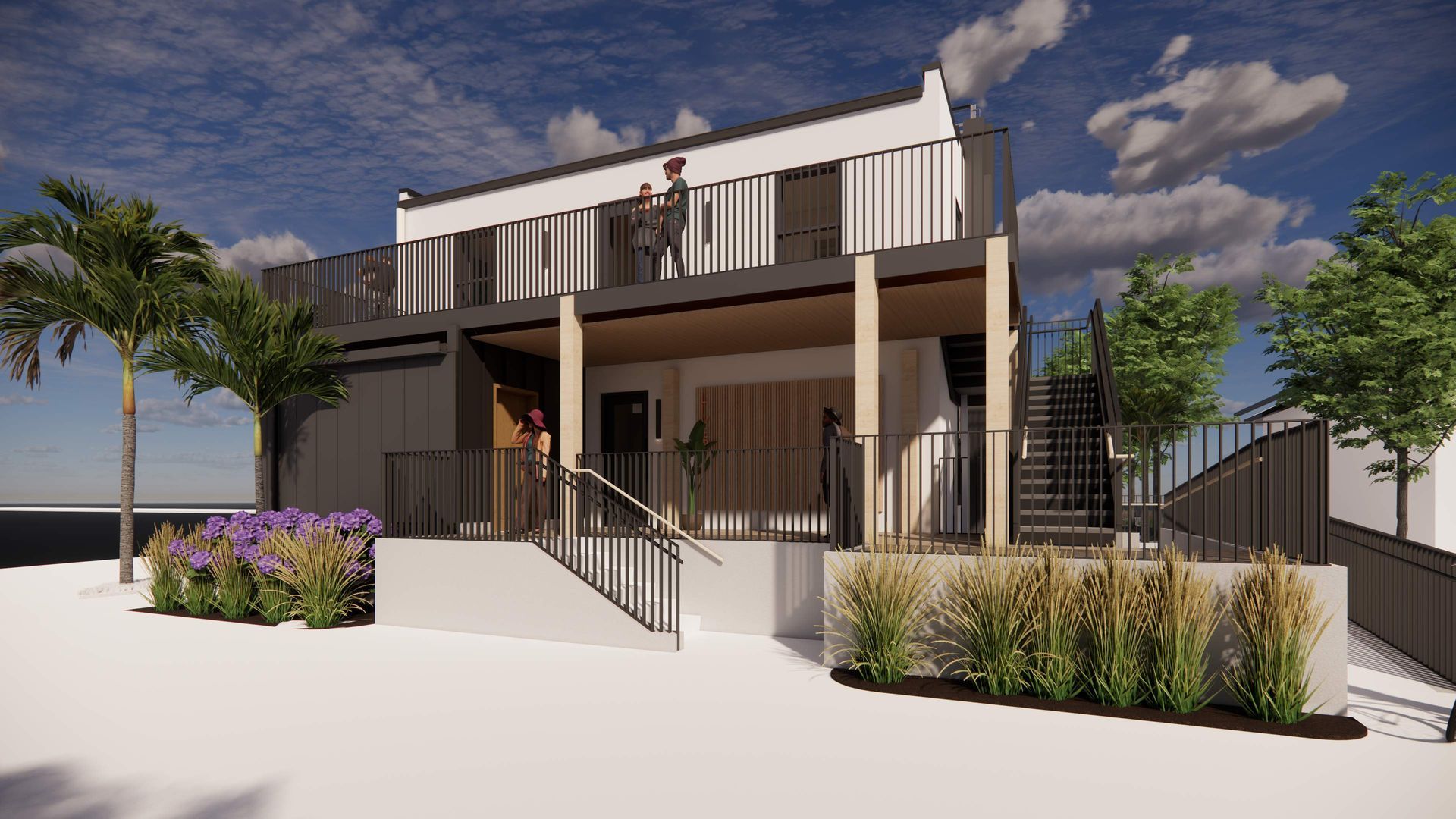 Modern two-story building with a balcony, stairs, and a shaded patio. Palm trees and other plants surround the structure.