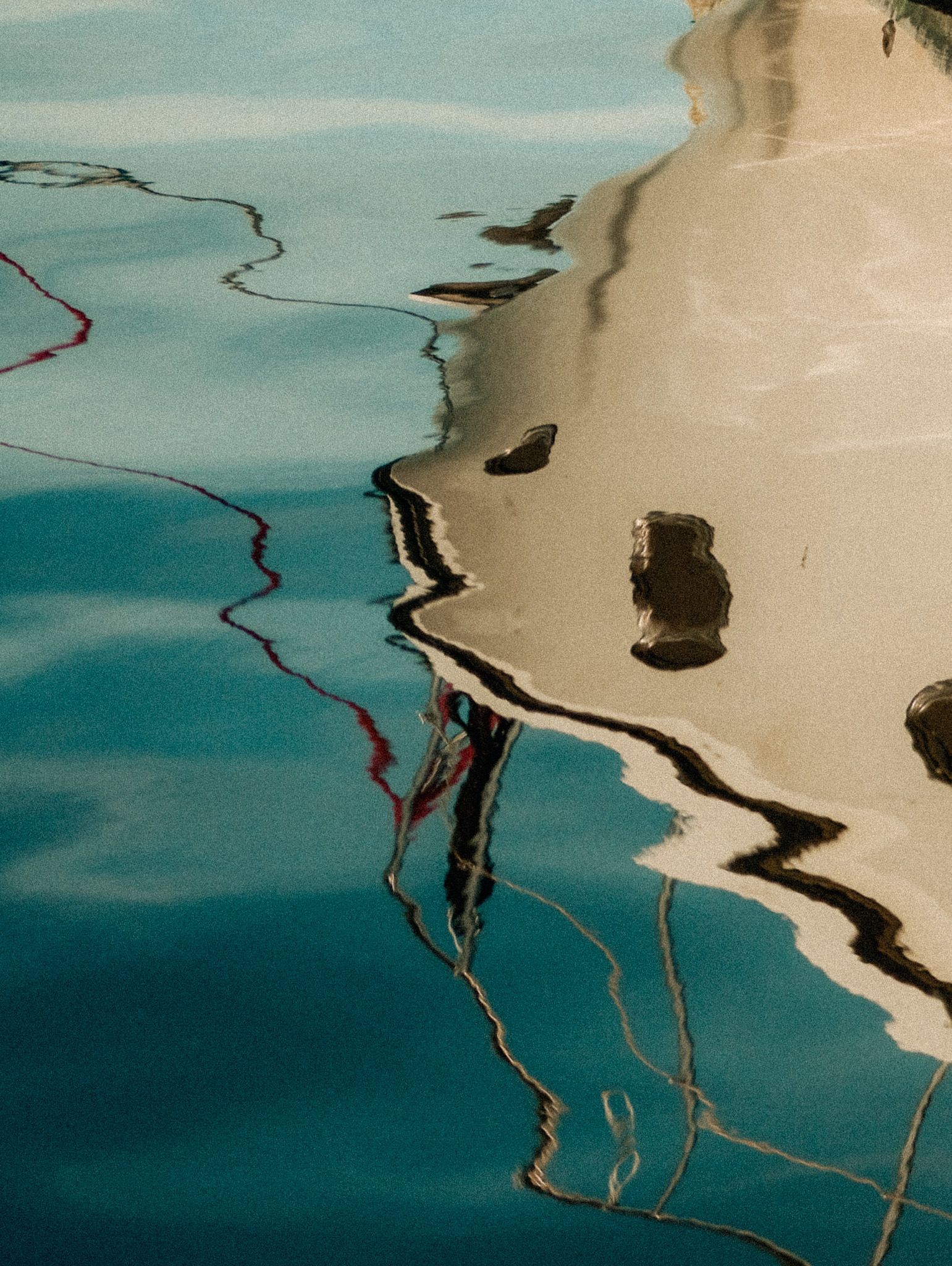 Abstract view of rippling blue water beside a beige shoreline or pool edge