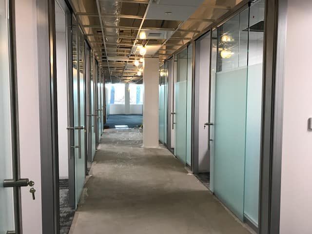 A long hallway with a lot of glass doors in an office building.