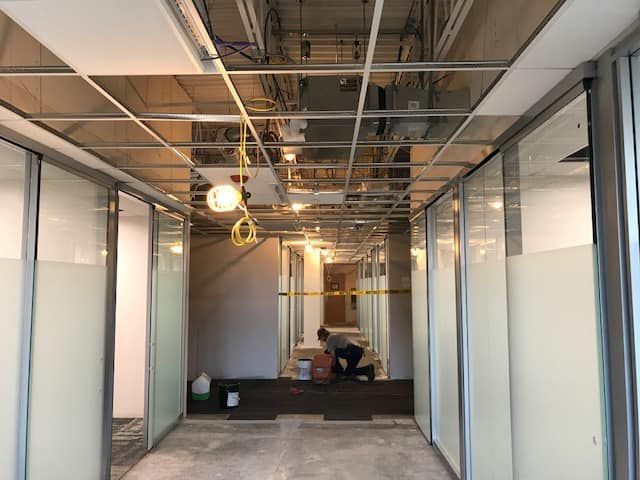 A man is kneeling down in a hallway in a building under construction.