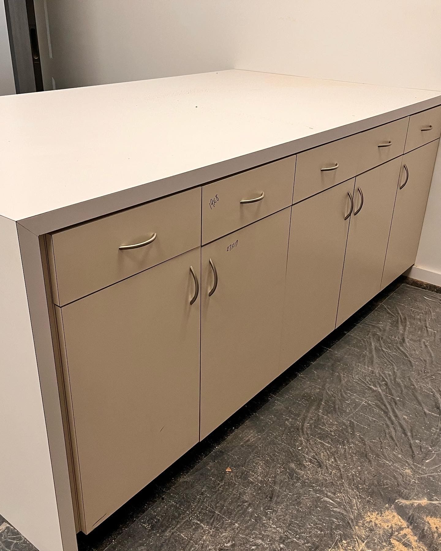 A long white cabinet with drawers and doors in a room.