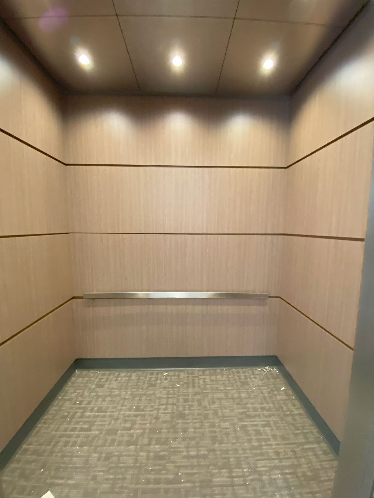 An empty elevator with wood paneling and a carpeted floor