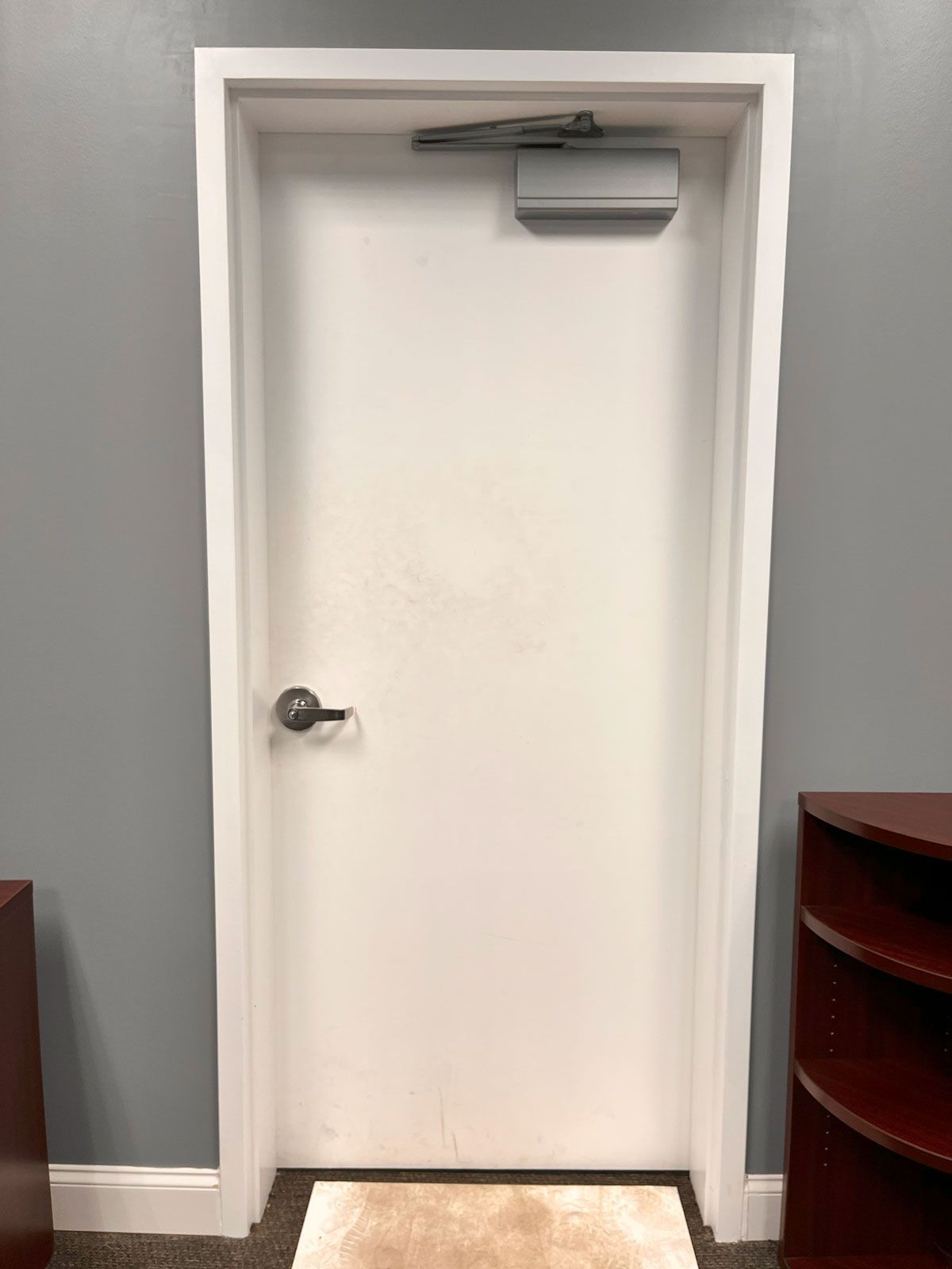 A white door in a room with a rug on the floor.