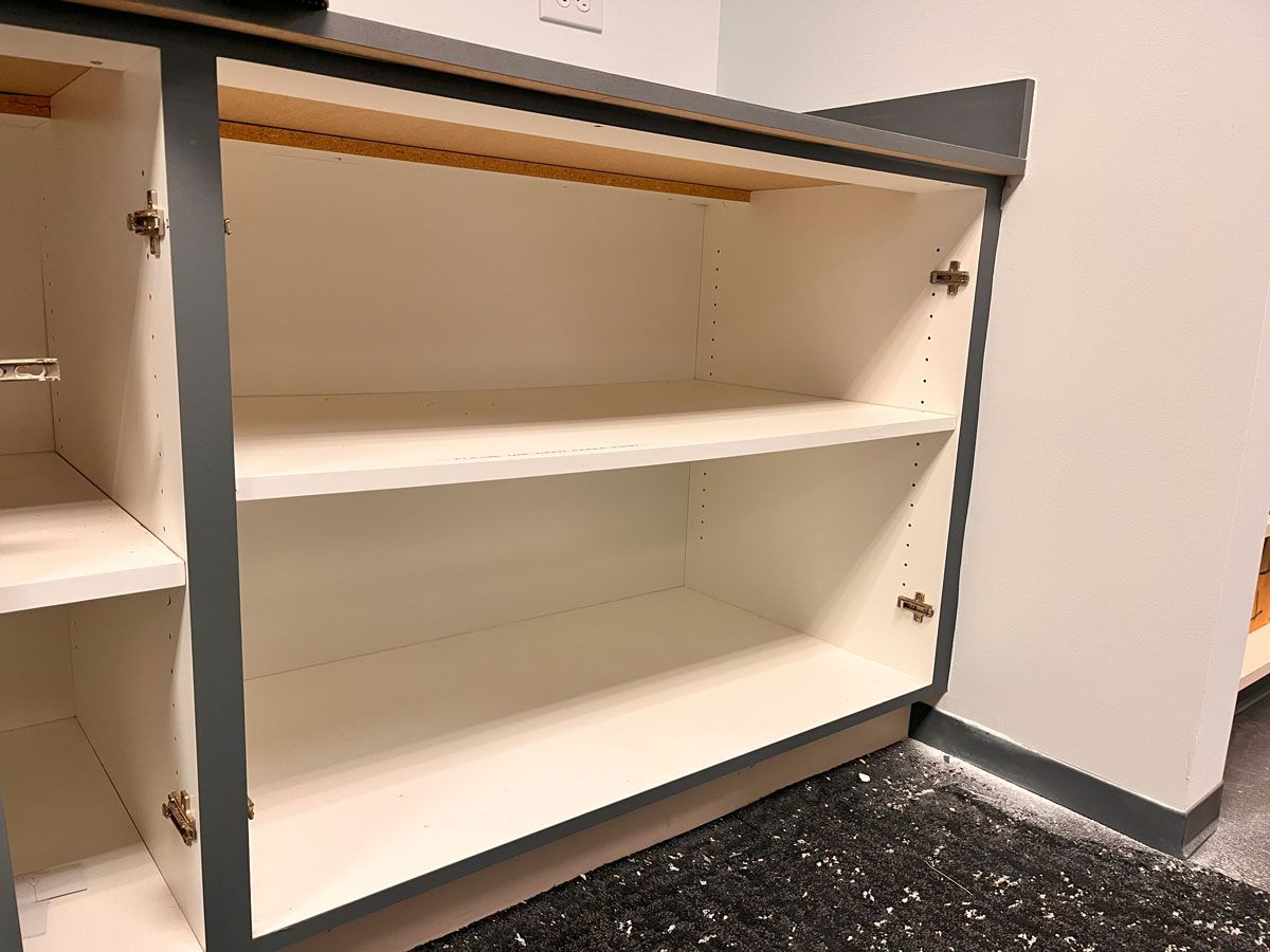 An empty shelf in a cabinet with the doors open.