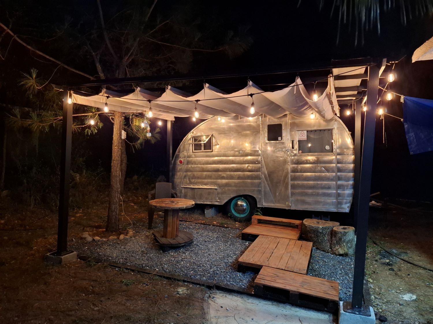 Un remolque plateado está estacionado bajo un toldo por la noche.