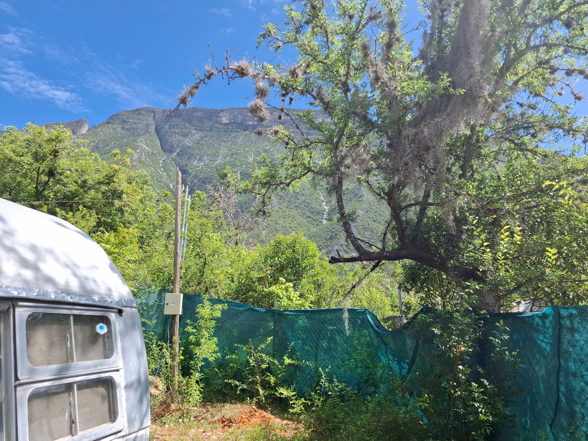 Un remolque Airstream está estacionado en un campo con una montaña al fondo.