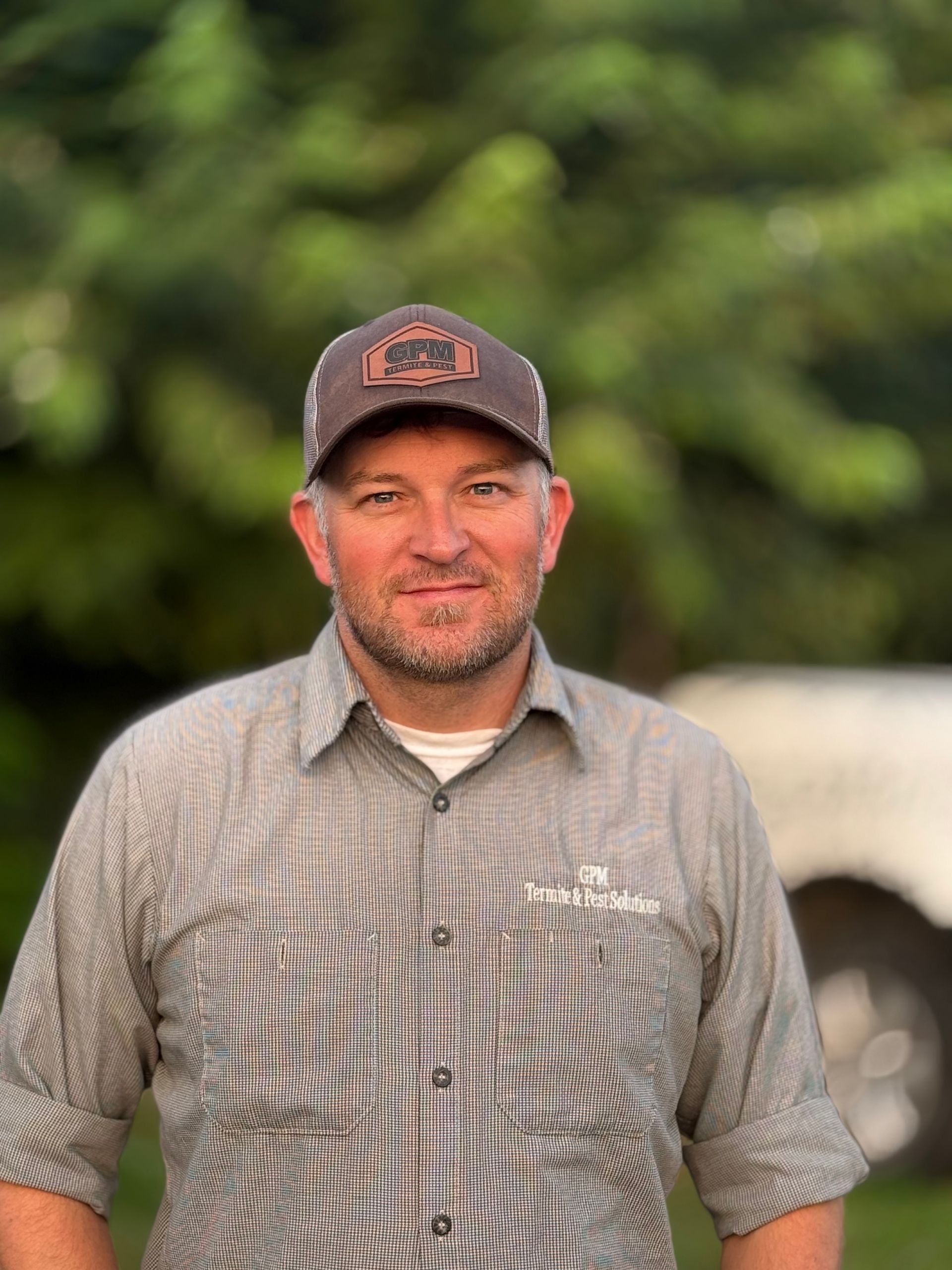 A man wearing a hat and a striped shirt is standing in front of a white truck.