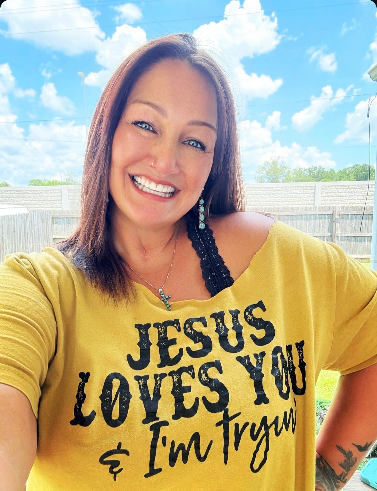 A woman is wearing a yellow shirt that says jesus loves you and i 'm trying.