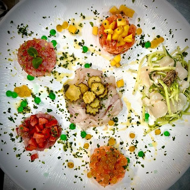 Piatto di piatti assortiti di pesce crudo, con guarnizioni colorate.
